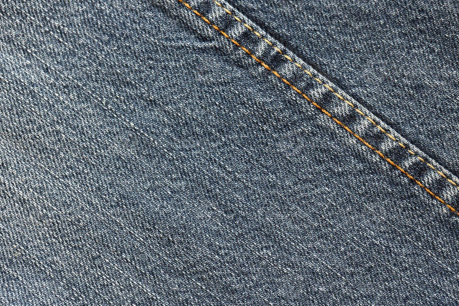 Detailed abstract texture of dark blue denim cloth. Background image of old used denim trousers fabric photo