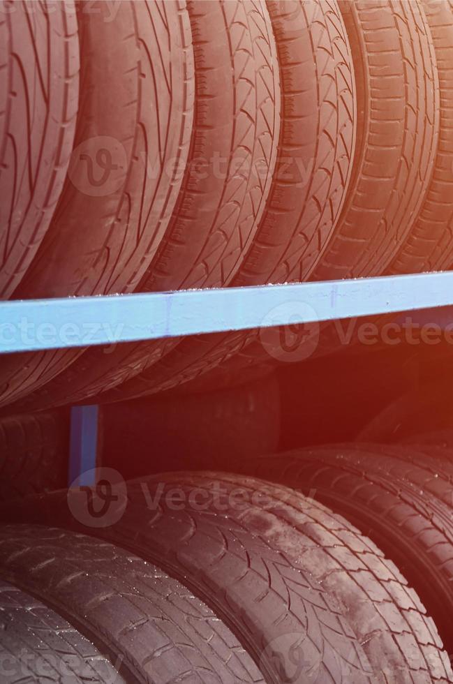 Rack with variety of car tires in automobile store. Many black tires. Tire stack background photo