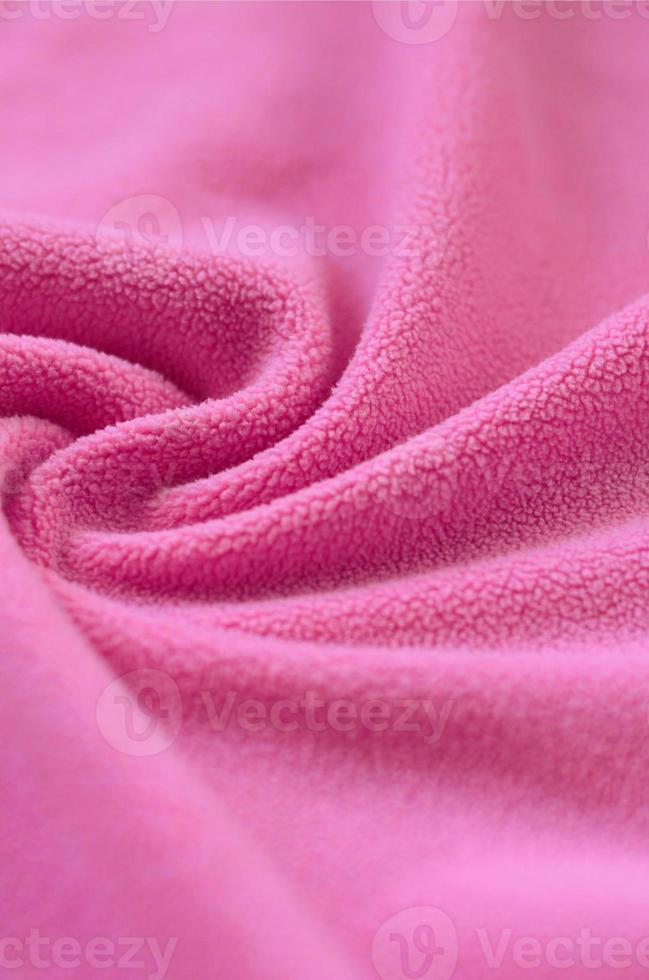 The blanket of furry pink fleece fabric. A background of light pink soft plush fleece material with a lot of relief folds photo