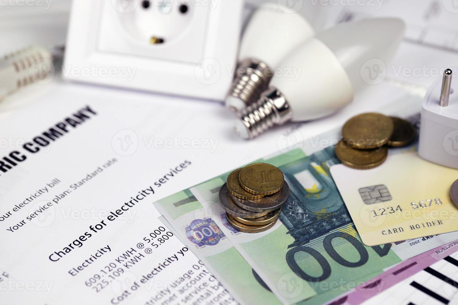 Calculator and Euro bills with pen on european electricity bill. Concept of saving money by using energy savings led light bulbs and electric bill payment photo