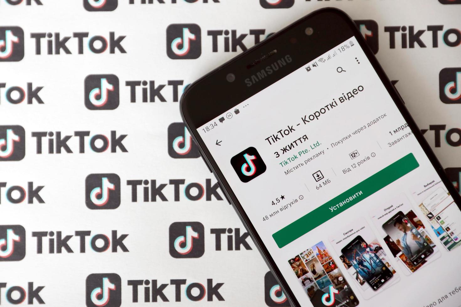 TERNOPIL, UKRAINE - MAY 2, 2022 Tik Tok smartphone app on screen and Many TikTok logo printed on paper. Tiktok or Douyin is a famous Chinese short-form video hosting service owned by ByteDance photo