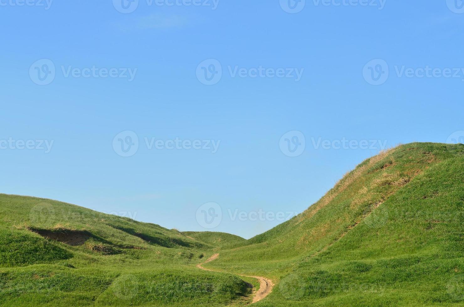 Landscape with a trampled path, passing through a wonderful green mountainous terrain. Photo of beautiful landscaped relief space with a thin path