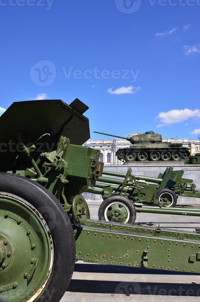 Photo of three guns of the Soviet Union of the Second World War against the background of the green tank T-34