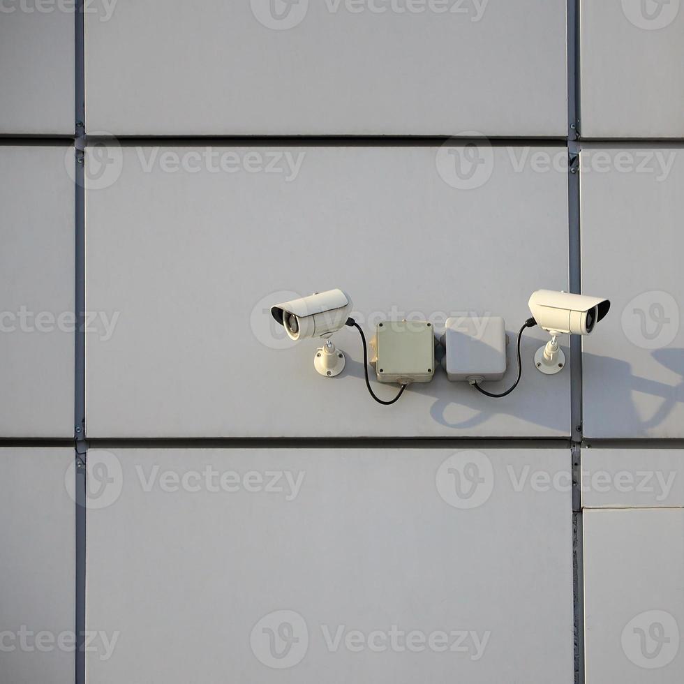 White surveillance camera built into the metal wall of the office building photo