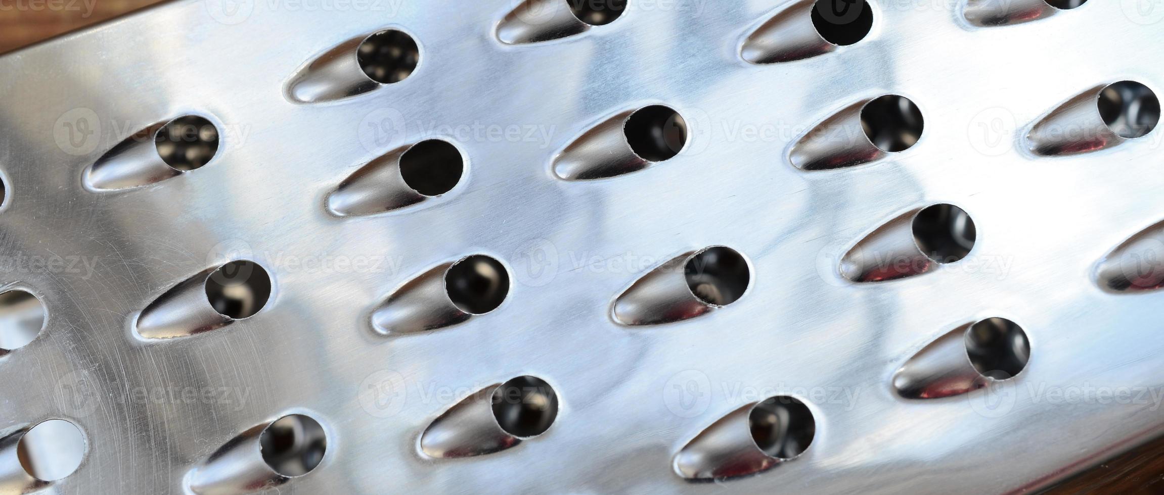 A fragment of a metal chrome grater close-up. Texture of blades for grinding food photo