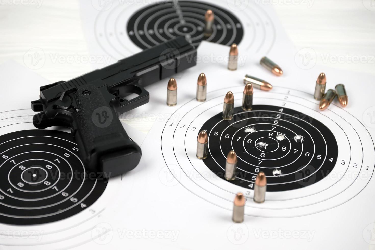Gun and many bullets shooting targets on white table in shooting range polygon. Training for aiming and shooting photo