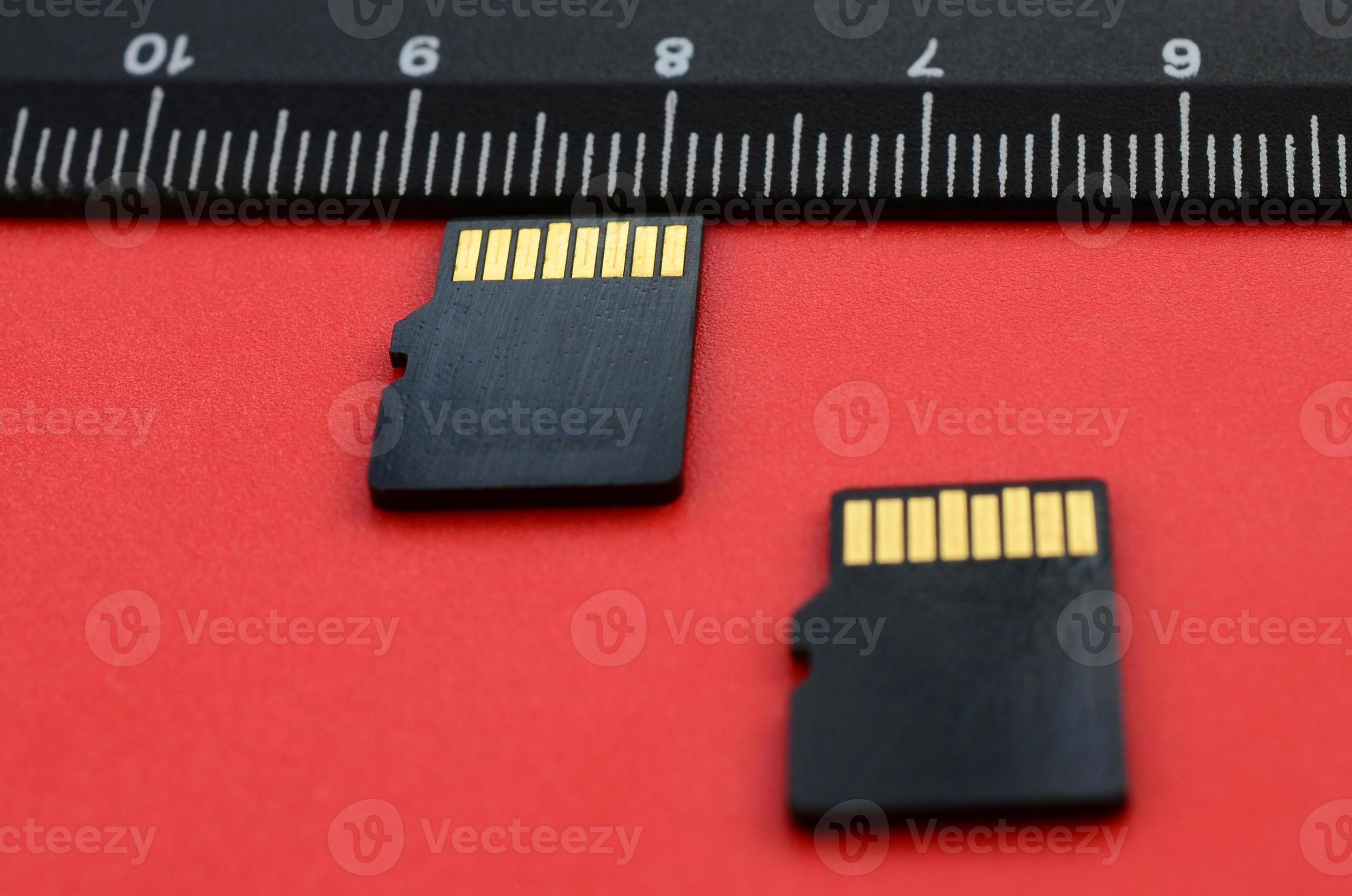 Two Small Micro SD Memory Cards Lie On A Red Background Next To A Black two-small-micro-sd-memory-cards-lie-on-a-red-background-next-to-a-black