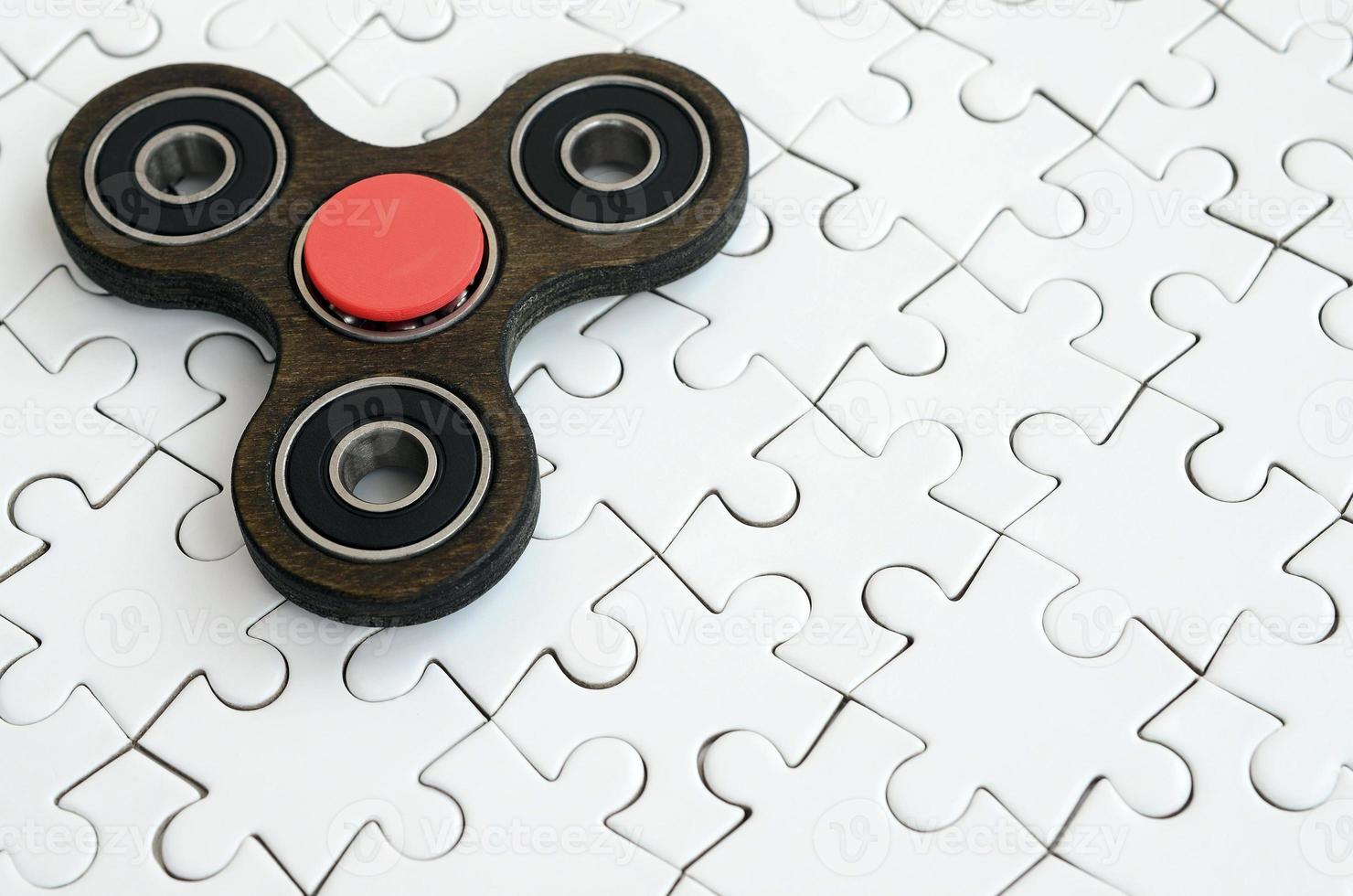 A wooden spinner lies on a white jigsaw puzzle background photo