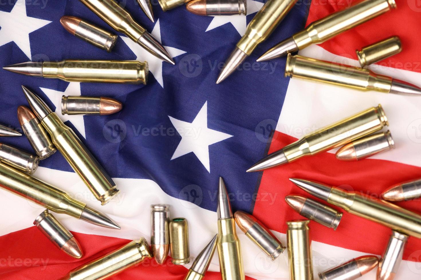 Many yellow 9mm and 5.56mm bullets and cartridges on United States flag. Concept of gun trafficking on USA territory or special ops photo