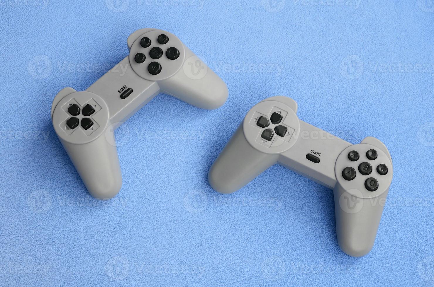 Playing games concept. Two pad joysticks lies on the blanket of furry blue fleece fabric. Controllers for video games on a background texture of light blue soft plush fleece material photo