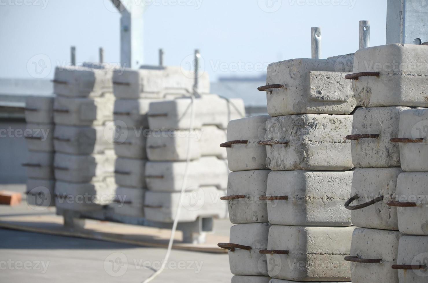 Counter weight or weight balance concrete blocks or bricks as part of suspended wire rope platform for facade works on high multistorey buildings. Many blocks with metal handles photo