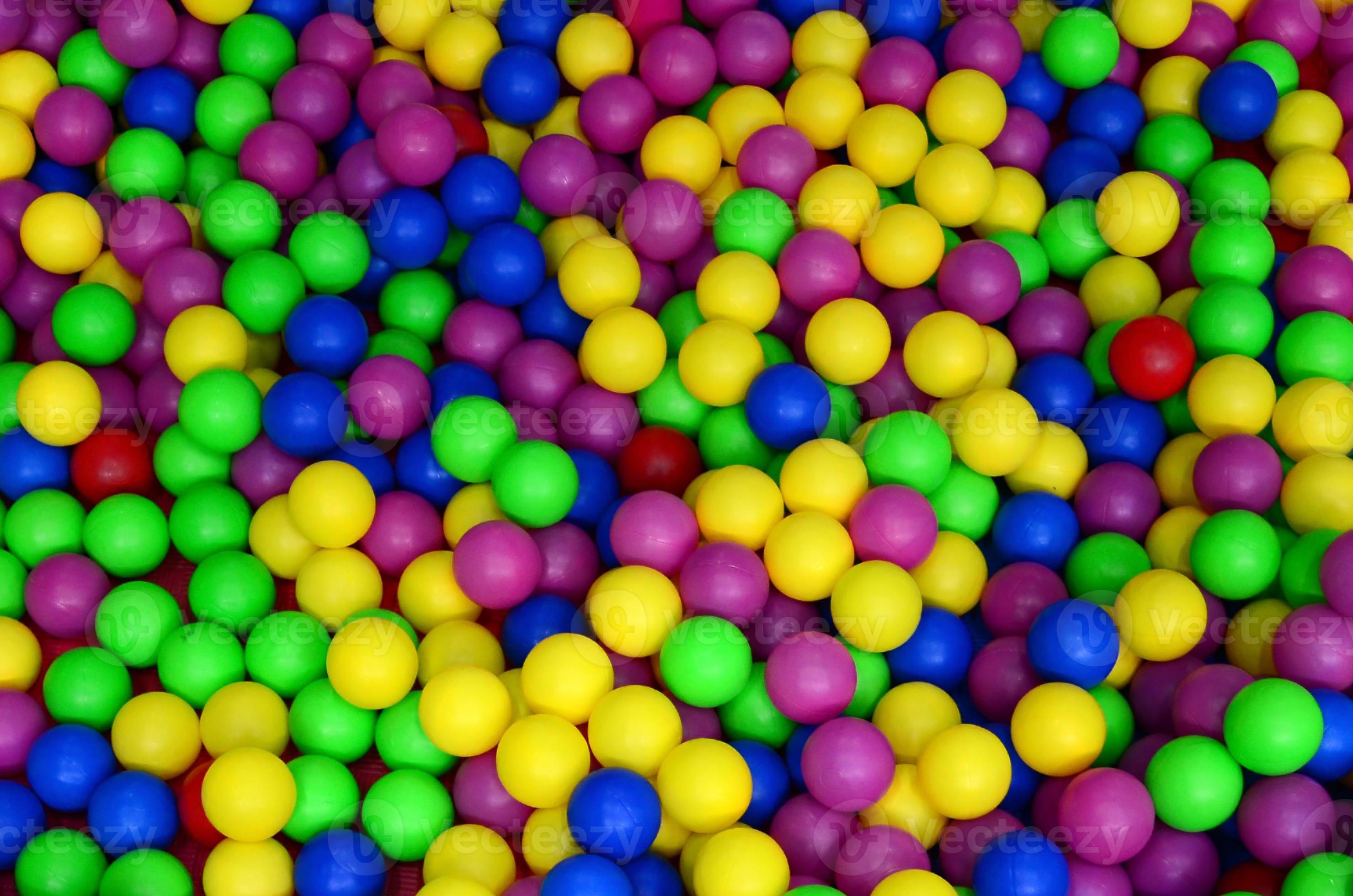 Many colorful plastic balls in a kids' ballpit at a playground. Close