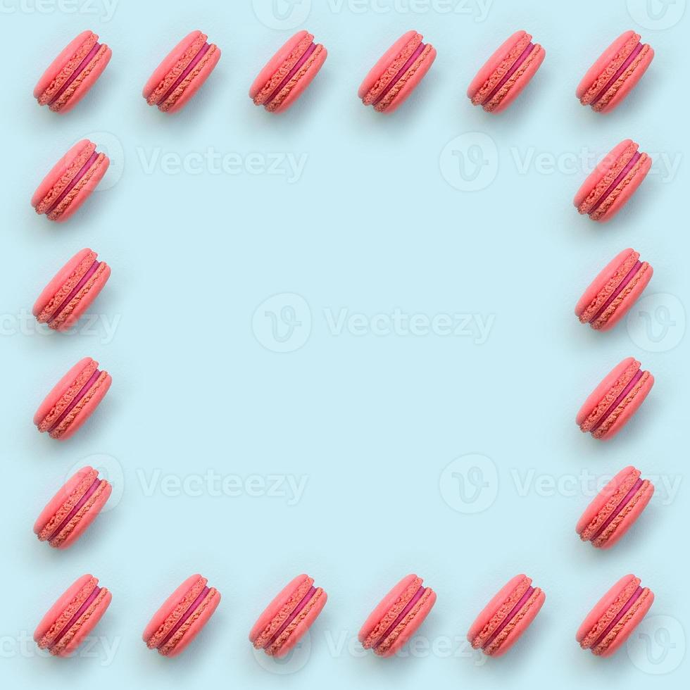 Pink dessert cake macaron or macaroon on trendy pastel blue background top view. Flat lay pattern composition photo