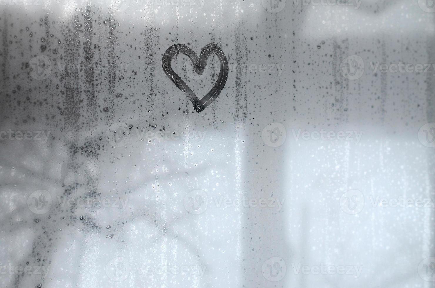 The heart is painted on the misted glass in winter photo