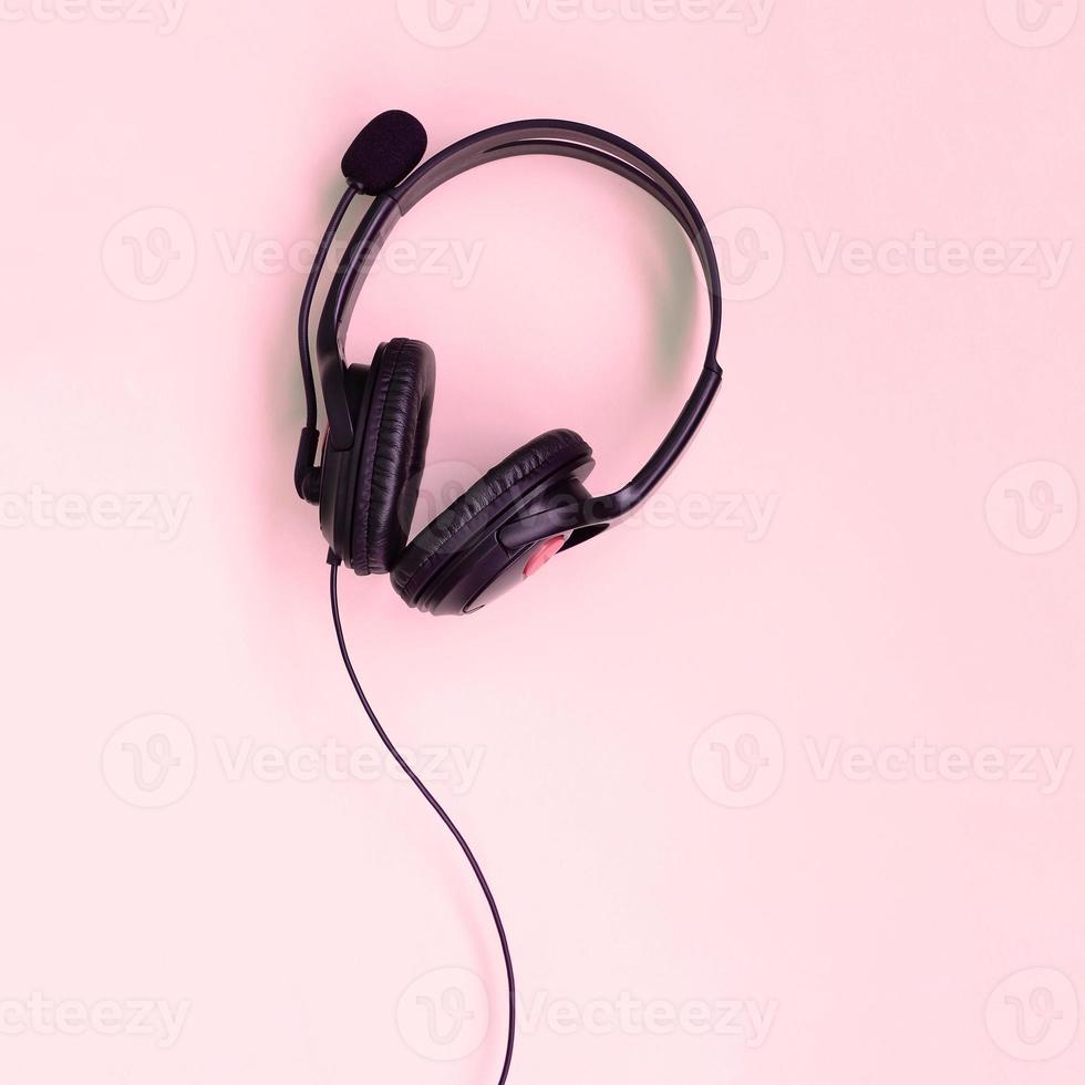 concepto de escuchar música. los auriculares negros se encuentran en el fondo rosa foto