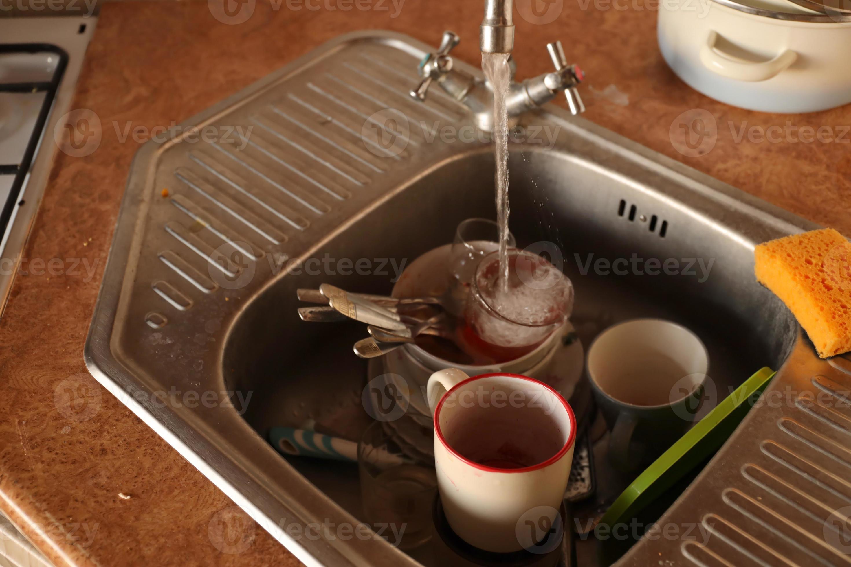 Stack of dirty dishes with food leftovers in the kitchen sink. Unwashed