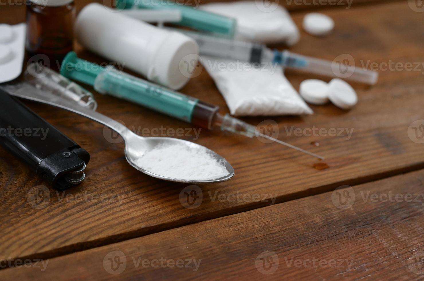 A lot of narcotic substances and devices for the preparation of drugs lie on an old wooden table photo