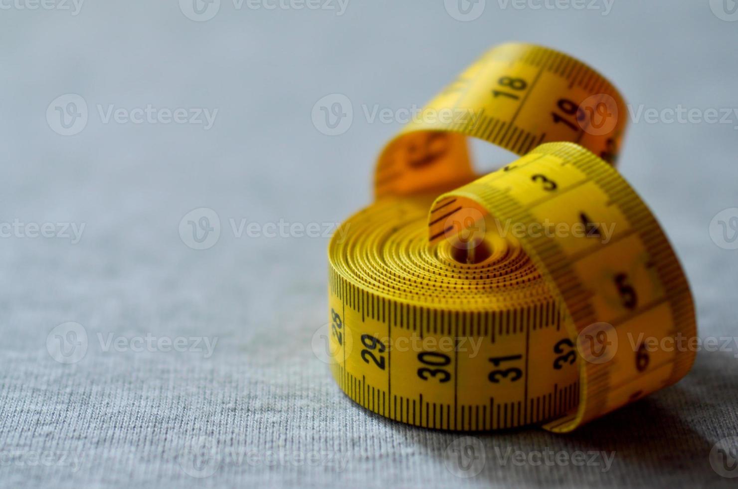 Yellow measuring tape lies on a gray knitted fabric photo