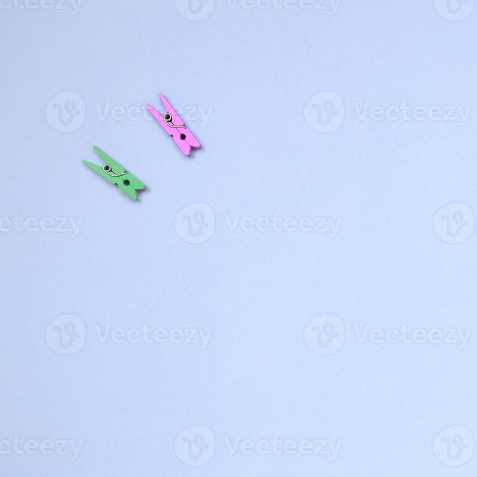 dos clavijas de madera de colores yacen sobre la textura del fondo del papel de color violeta pastel de moda foto