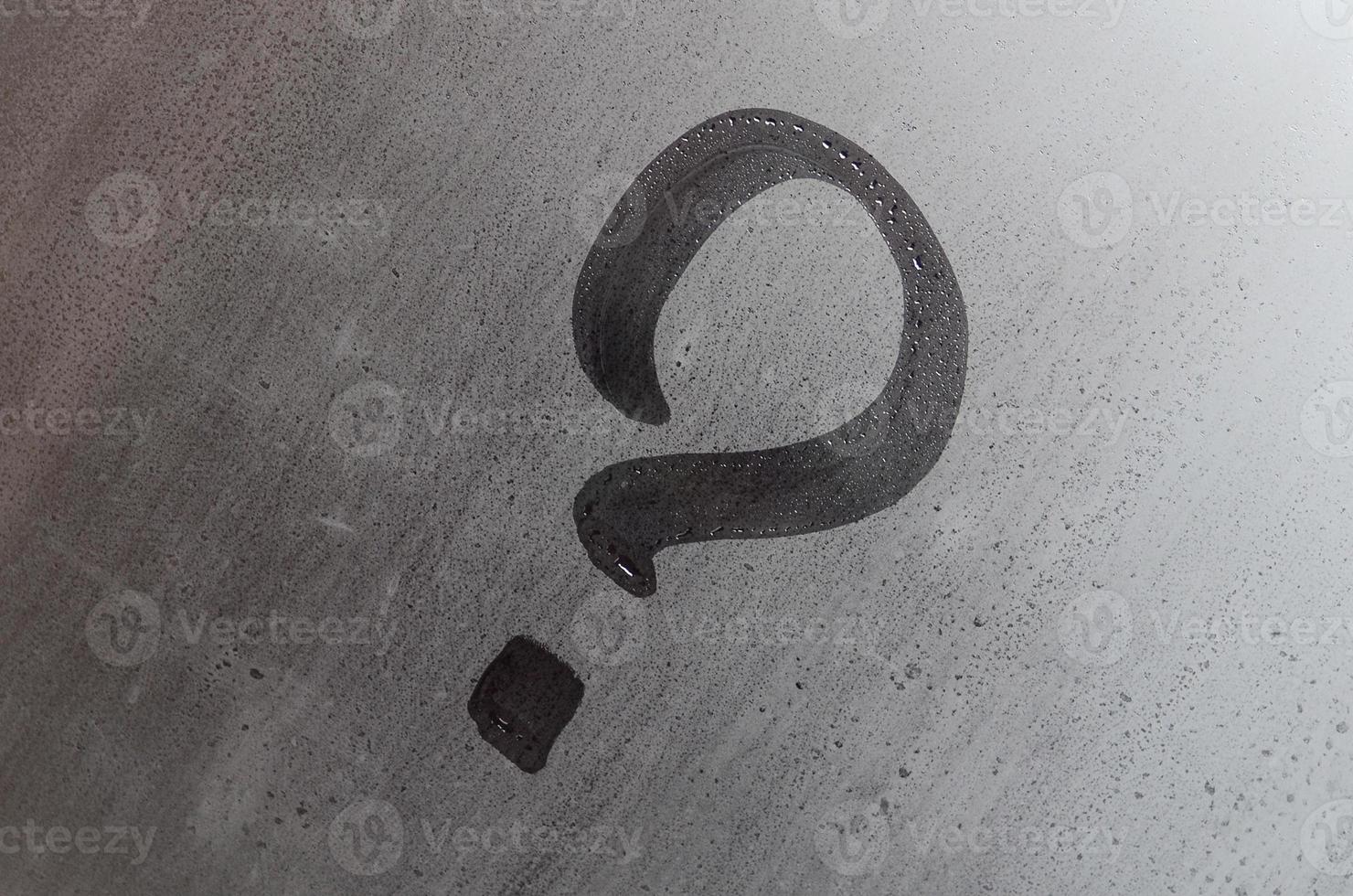 The inscription on glass, question mark concept. Question sign is painted on the surface of misted and wet window photo