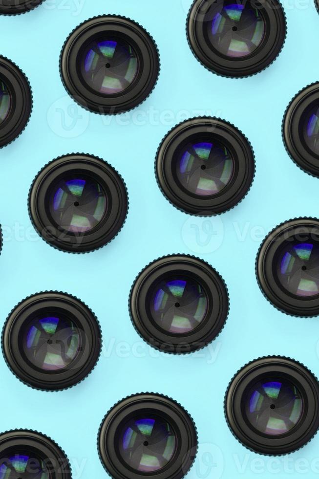 A few camera lenses with a closed aperture lie on texture background of fashion pastel blue color paper photo