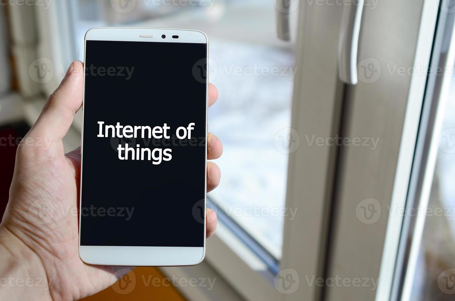 A person sees a white inscription on a black smartphone display that holds in his hand. Internet of things photo