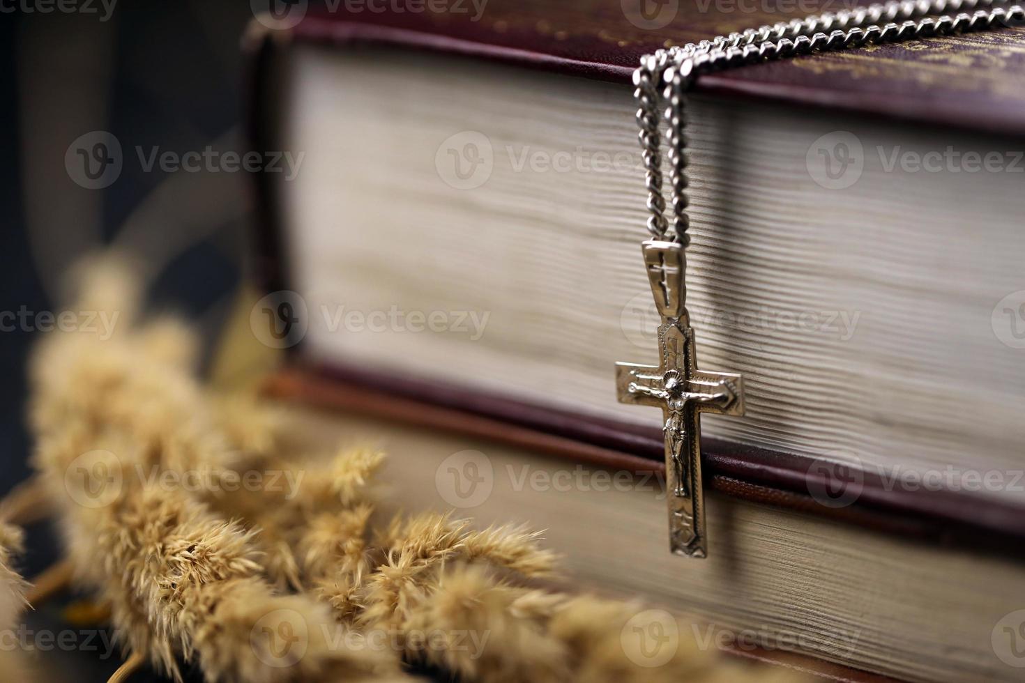 Silver necklace with crucifix cross on christian holy bible book on black wooden table. Asking blessings from God with the power of holiness photo