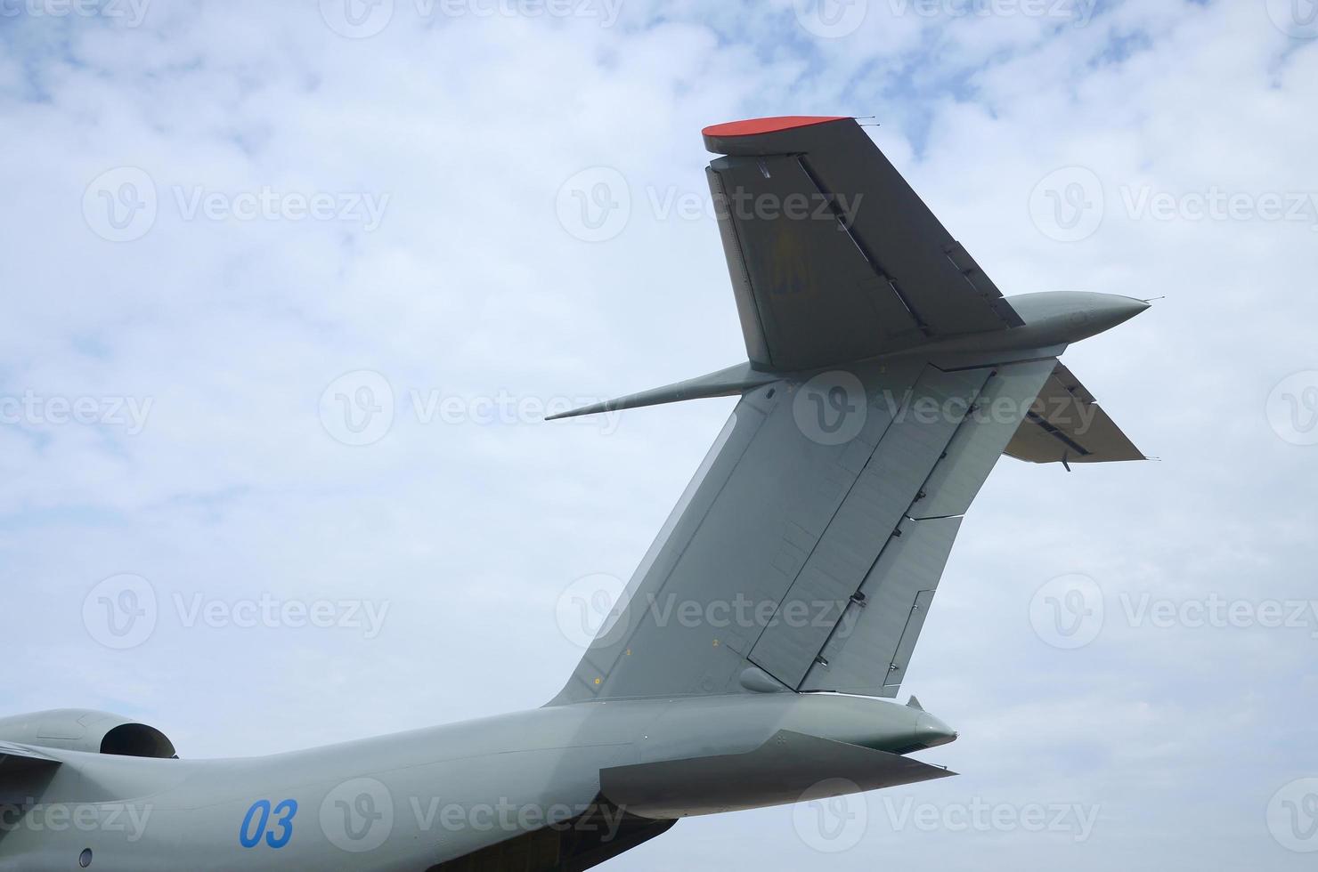 Big tail of armoured military aircraft close up against blue sky photo