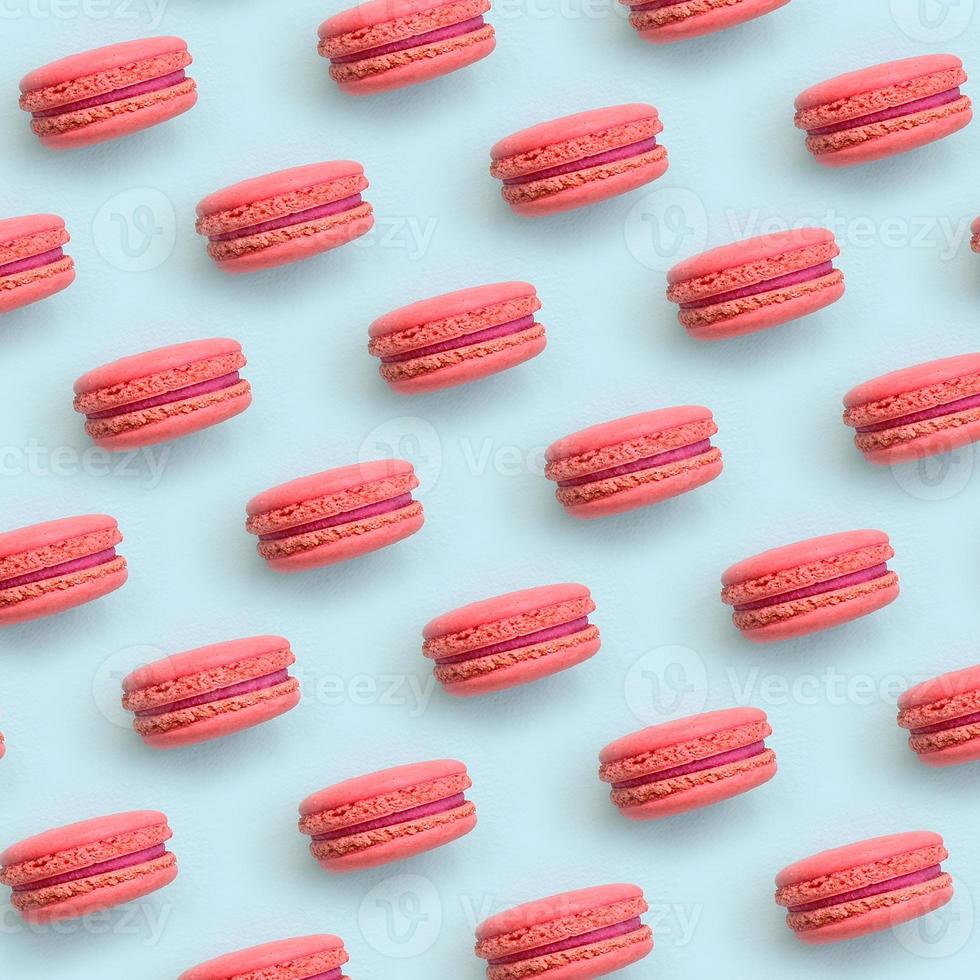 Pink dessert cake macaron or macaroon on trendy pastel blue background top view. Flat lay pattern composition photo