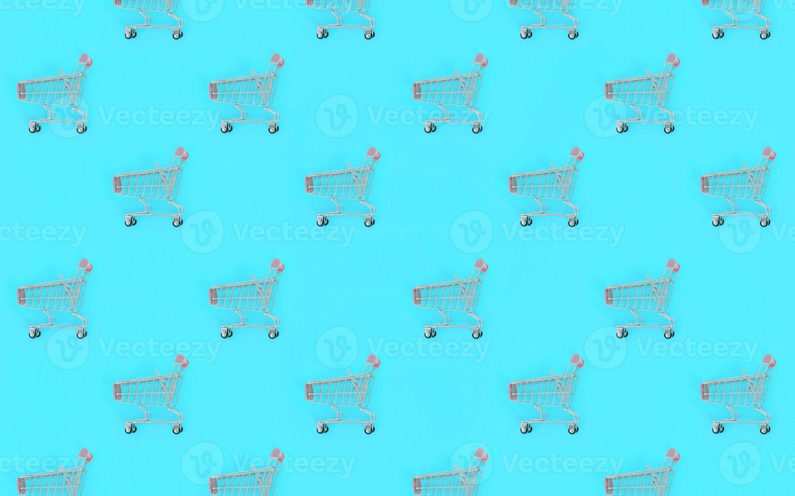 Shopping addiction, shopping lover or shopaholic concept. Many small empty shopping carts perform a pattern on a pastel colored paper background. Flat lay composition, top view photo