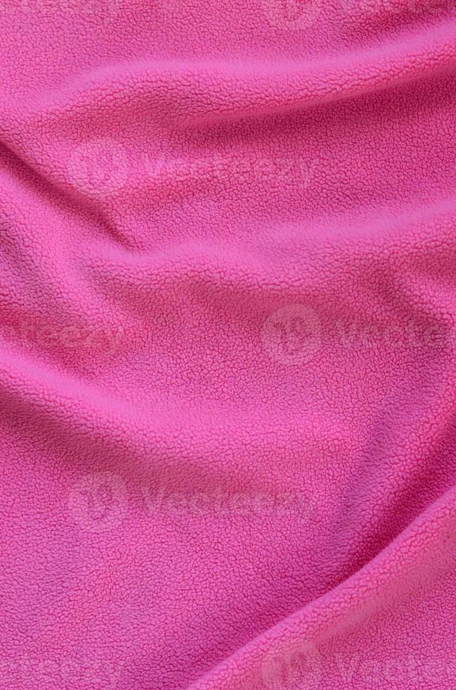 The blanket of furry pink fleece fabric. A background of light pink soft plush fleece material with a lot of relief folds photo