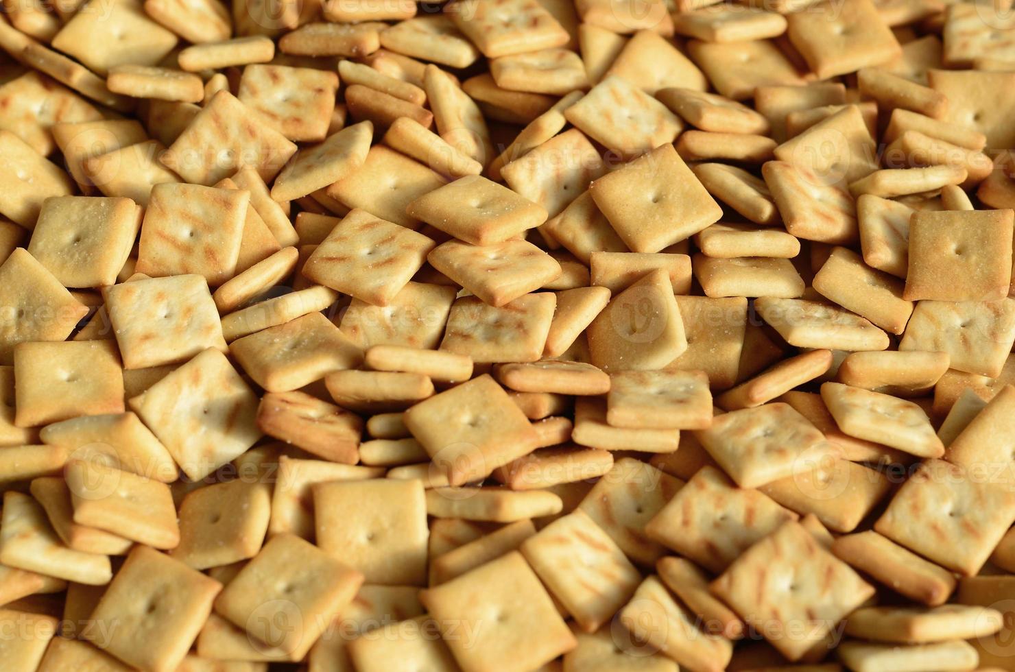 Background texture of small edible squares baked from dough and sprinkled with salt. A lot of salt cracker photo