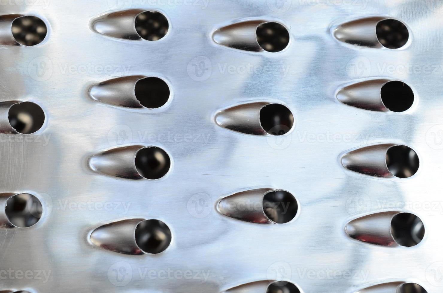 A fragment of a metal chrome grater close-up. Texture of blades for grinding food photo
