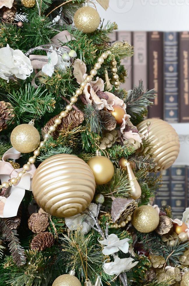 A beautiful decorated Christmas tree on the background of a bookshelf with many books of different colors. Christmas background image of the library photo