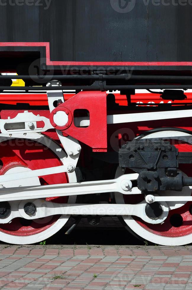 Wheels of the old black steam locomotive of Soviet times. The side of the locomotive with elements of the rotating technology of old trains photo