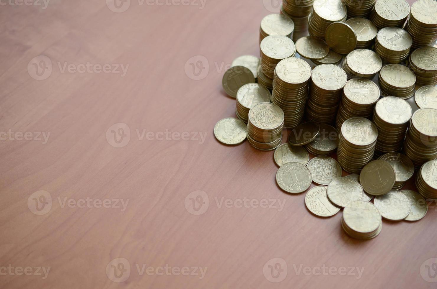 Big amount of shiny ukrainian old 1 hryvnia coins close up on wooden table. The concept of business and rich life in Ukraine photo