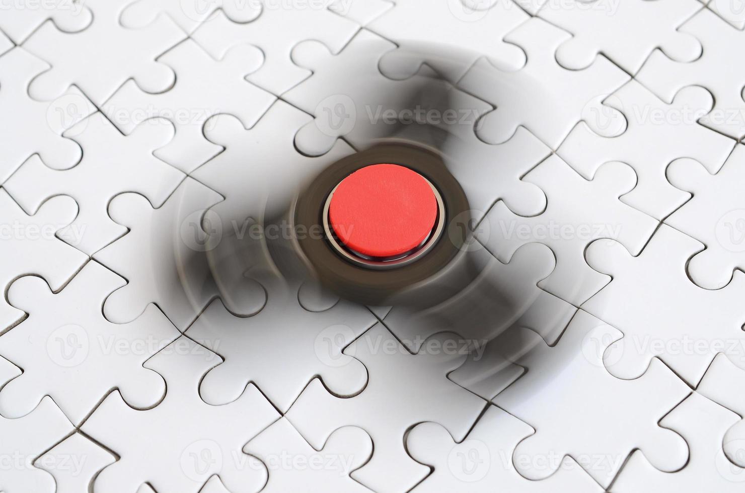 A wooden spinner spins on a white jigsaw puzzle background photo