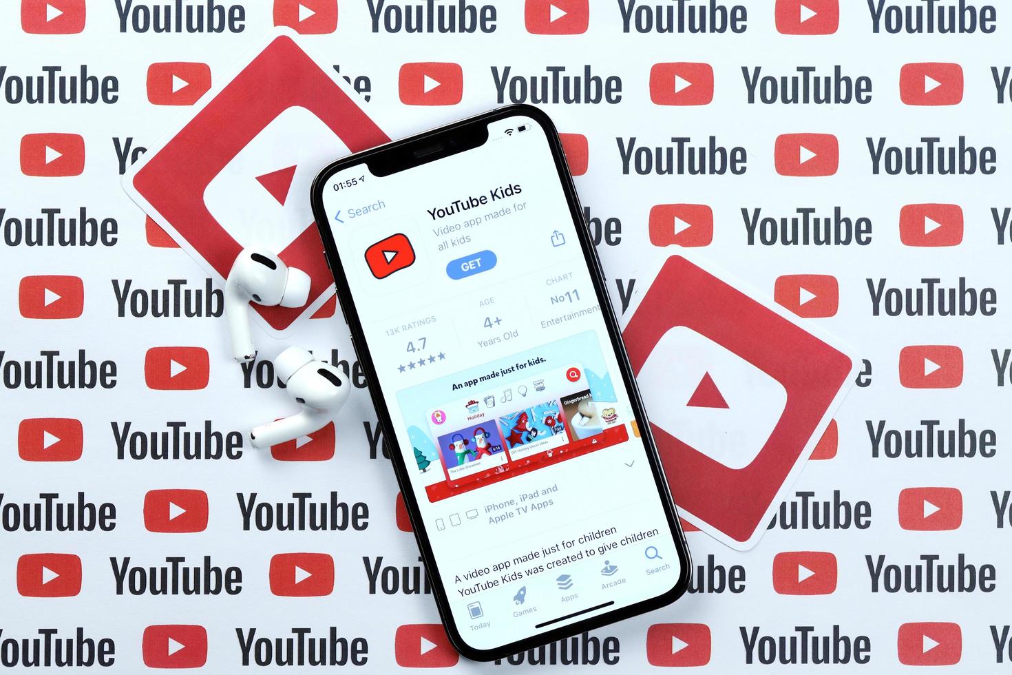 KHARKOV, UKRAINE - MARCH 5, 2021 Youtube kids icon and application from App store on iPhone 12 pro display screen with airpods pro on white table photo