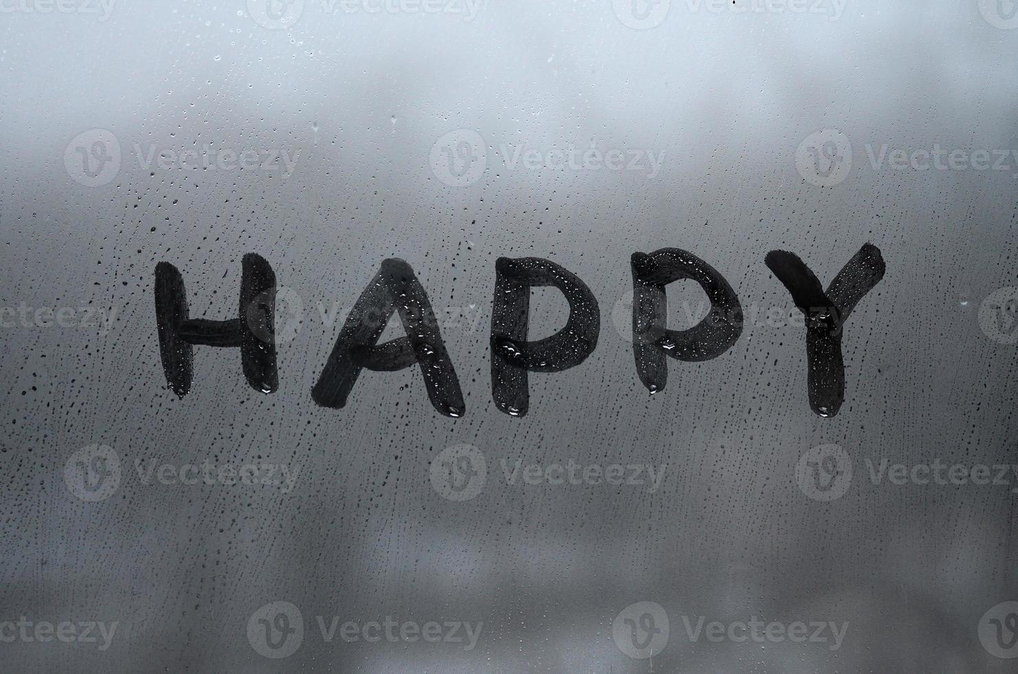 The English word Happy is written with a finger on the surface of the misted glass photo