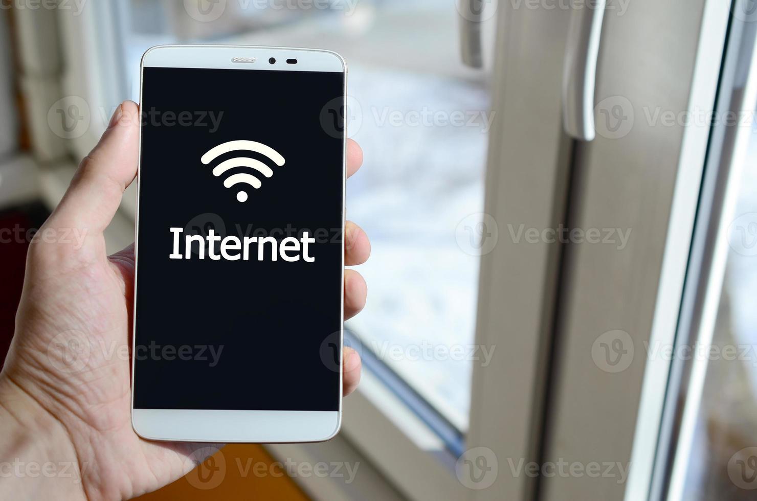 A person sees a white inscription on a black smartphone display that holds in his hand. Internet photo