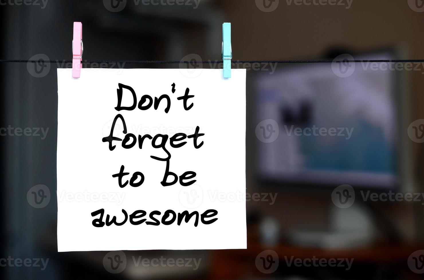 Don't forget to be awesome. Note is written on a white sticker that hangs with a clothespin on a rope on a background of office interior photo