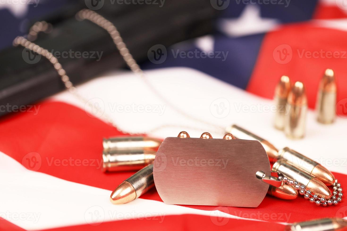 Many yellow 9mm bullets and gun with dogtags on United States flag. Concept of duty and service in US army forces photo
