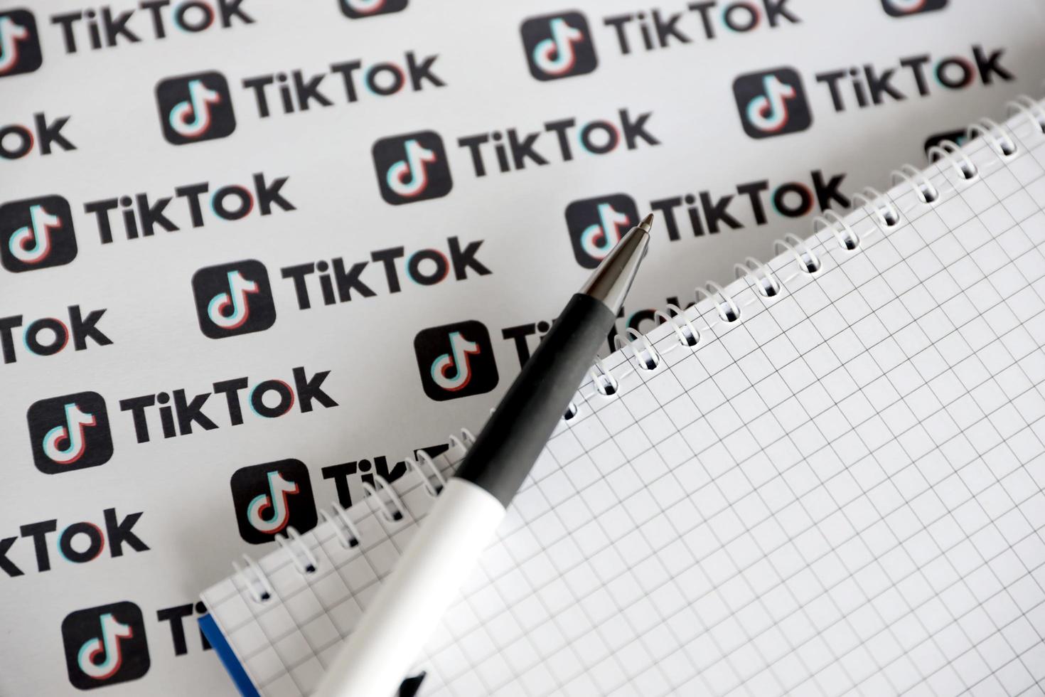 ternopil, ucrania - 2 de mayo de 2022 bloc de notas con bolígrafo y muchos logotipos de tiktok impresos en papel. tiktok o douyin es un famoso servicio chino de alojamiento de videos de formato corto propiedad de bytedance foto