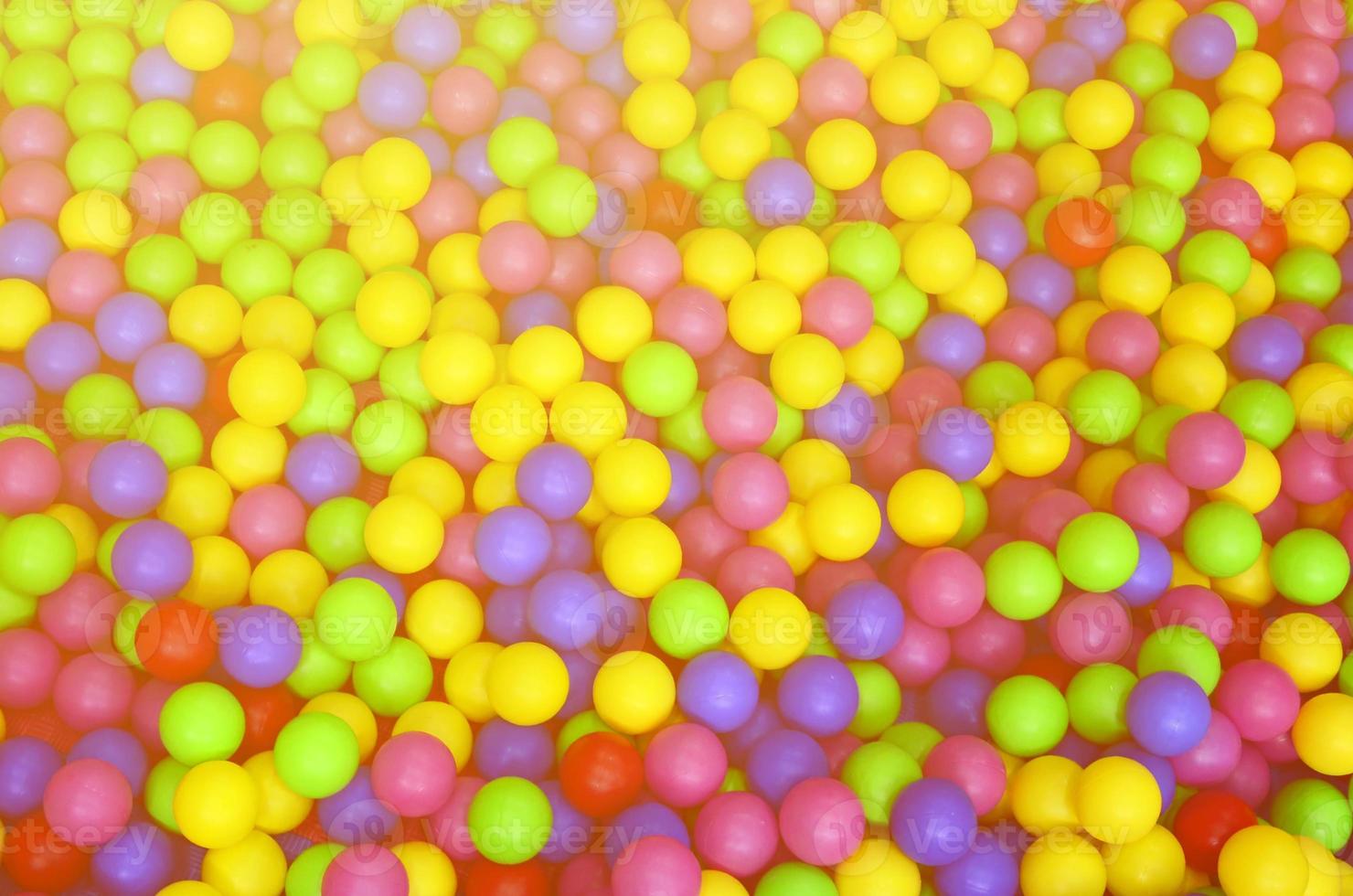 Many colorful plastic balls in a kids' ballpit at a playground. Close up pattern photo