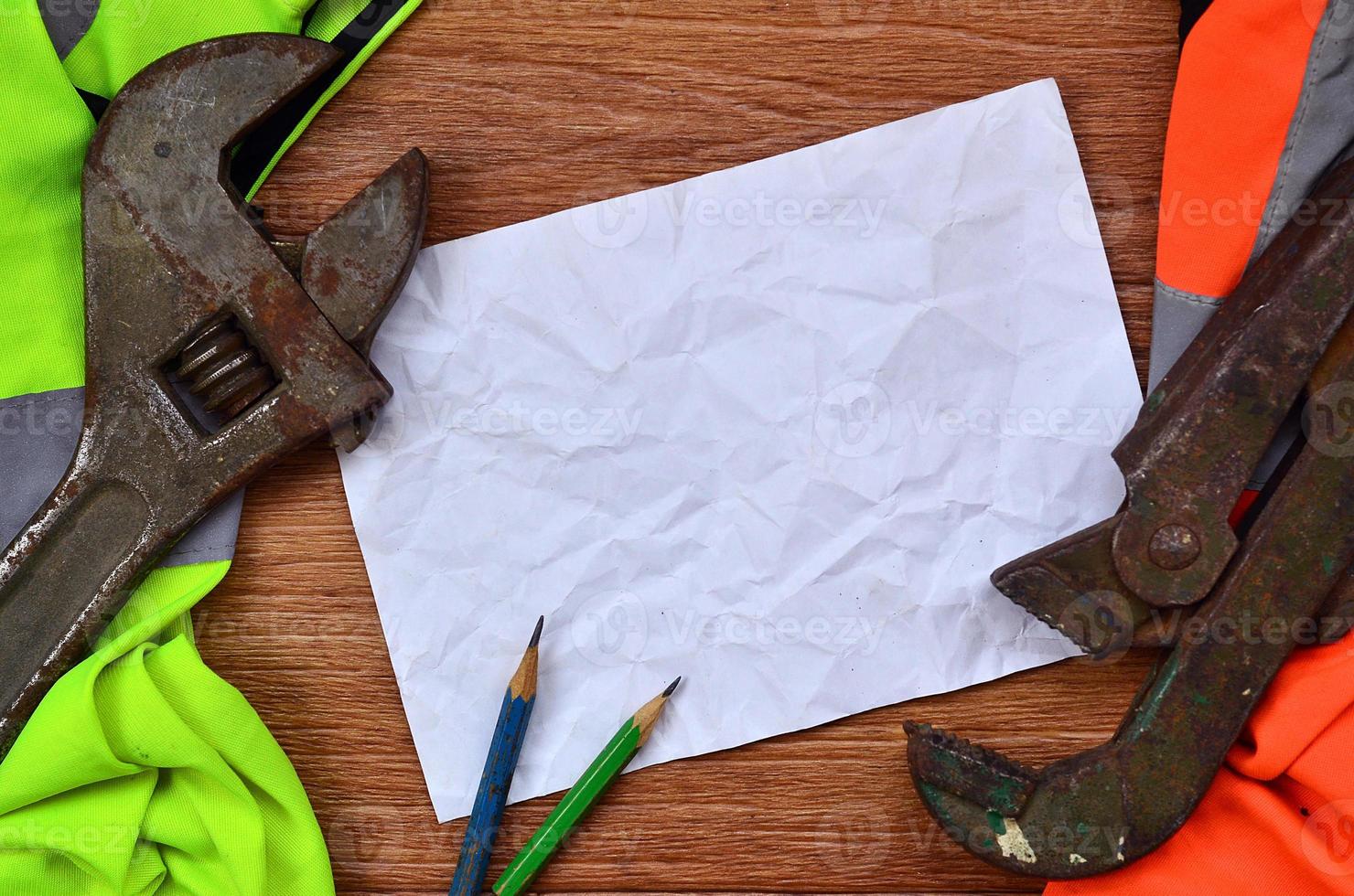 A crumpled sheet of paper with two pencils surrounded by green a photo