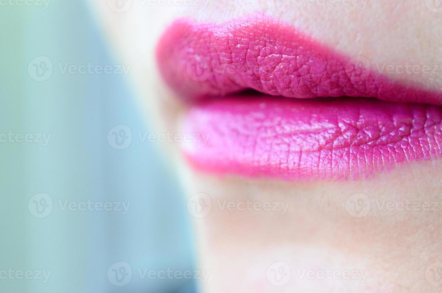 Close up shot of woman lips with glossy fuchsia lipstick photo