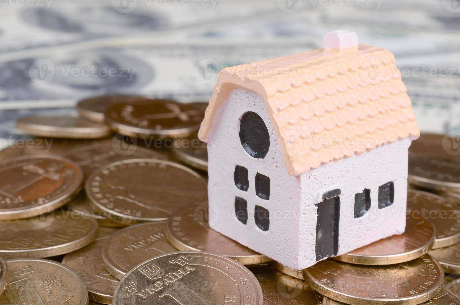 Mini house model on big coins stack on many dollar bills as background photo