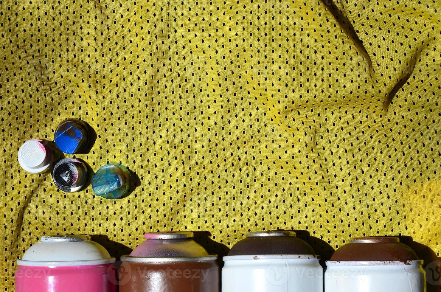 Several caps for used aerosol paint sprayers lie on the sports shirt of a basketball player made of polyester fabric. The concept of youth street art, active sports and eventful lifestyle photo