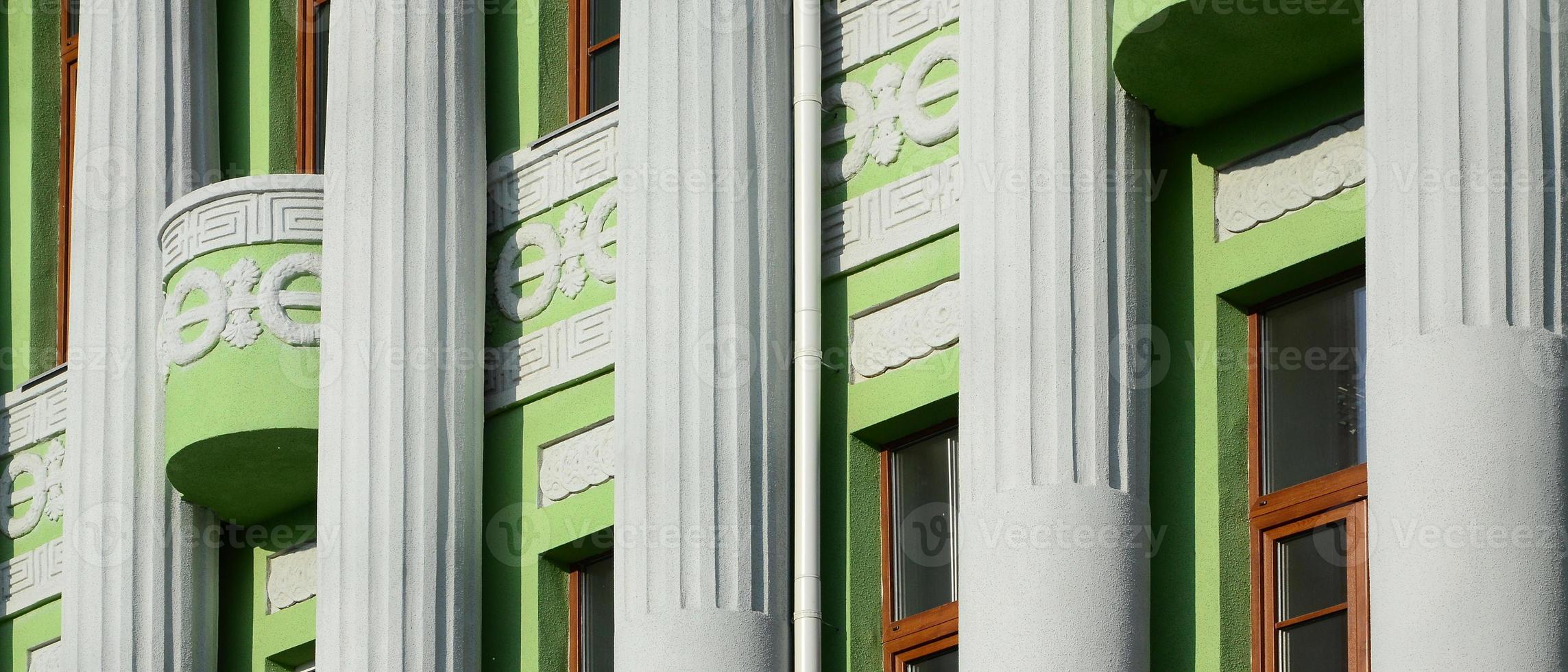 antiguo edificio restaurado de varias plantas con columnas antiguas, pintado de verde foto