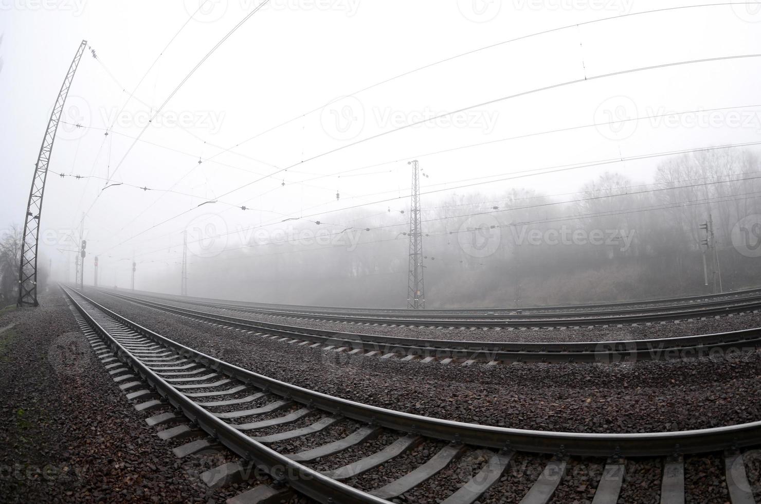 The railway track in a misty morning. A lot of rails and sleepers go into the misty horizon. Fisheye photo with increased distortion